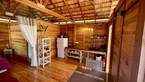 Un accogliente chalet in legno con angolo cottura, un piccolo frigorifero e una scaffalatura.