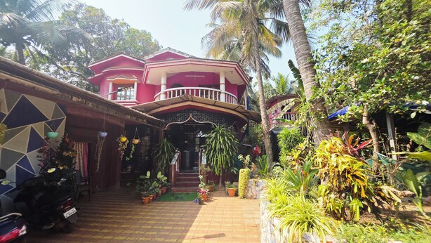 A two-story building with a balcony, potted plants, and a tiled entrance. - Vailankani guest house (Canacona)