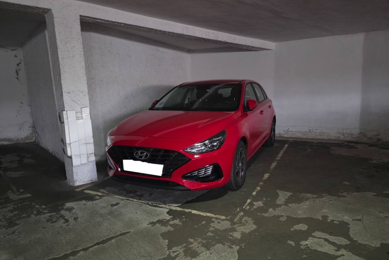 Un auto rojo estacionado en un estacionamiento poco iluminado.