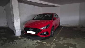 Un auto rojo estacionado en un estacionamiento poco iluminado.