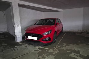 A red car parked in a dimly lit parking garage.