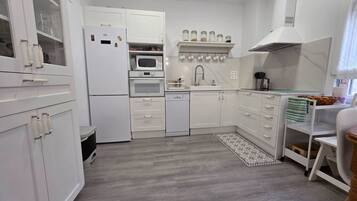 Cocina compacta con armarios blancos, microondas, horno, pileta y una mesada pequeña.