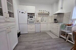 A compact kitchen with white cabinets, a microwave, oven, sink, and a small countertop.