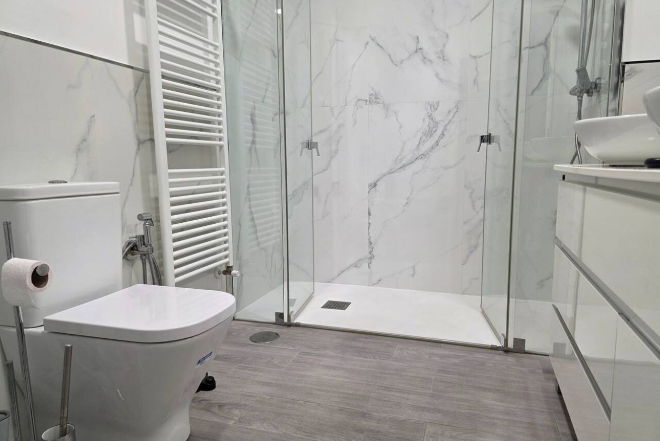 Un baño moderno con inodoro, ducha y lavamanos.