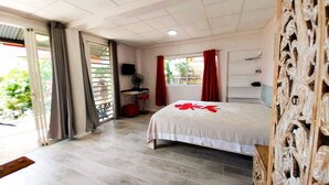 A hotel room with a bed, a desk, a chair, a TV, and a window with curtains. - TAHITI - Terevete Pool Studio (Arue)
