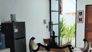 A dining area with a wooden table and chairs, a ceiling fan, a refrigerator, and a water dispenser. - Serene Bali Villa With Private Pool and Antiqued Charm (Denpasar)
