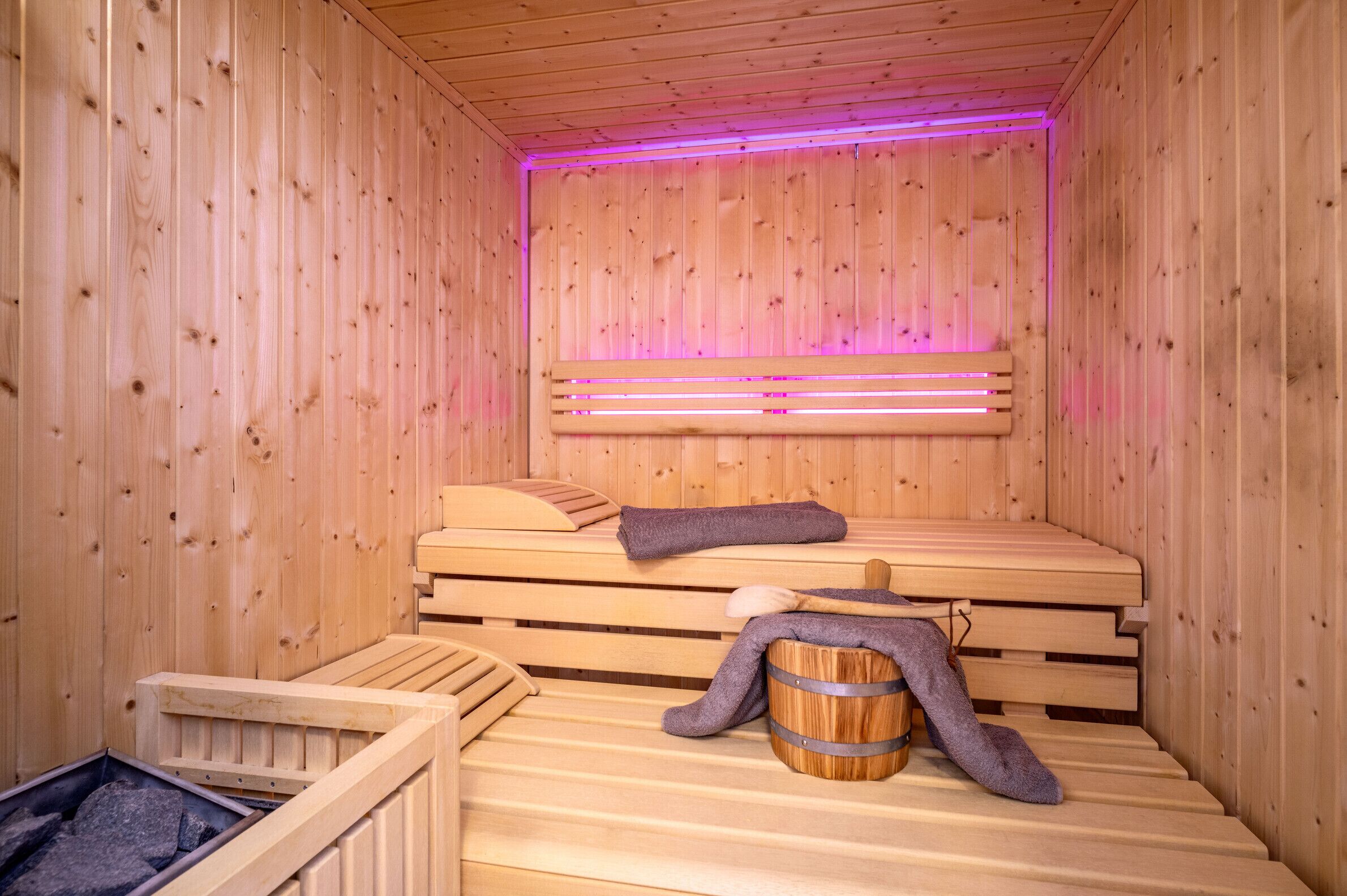 Una sauna de madera con bancos y un banco con una toalla y una cuchara de madera.