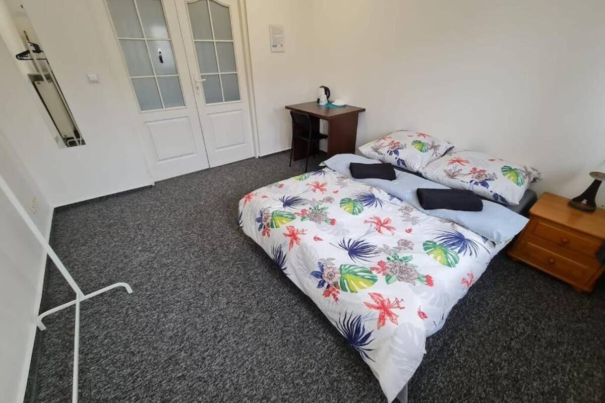 A bedroom with a bed, two bedside tables, a desk, and a wardrobe.