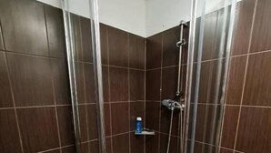 A glass-enclosed shower stall with dark brown tiles and a white floor. - Fantastic Inn Warsaw - NS42 (Warsaw)