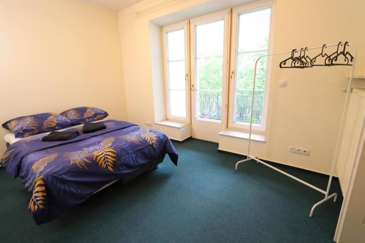 A bedroom with a bed, a window, and a coat rack.