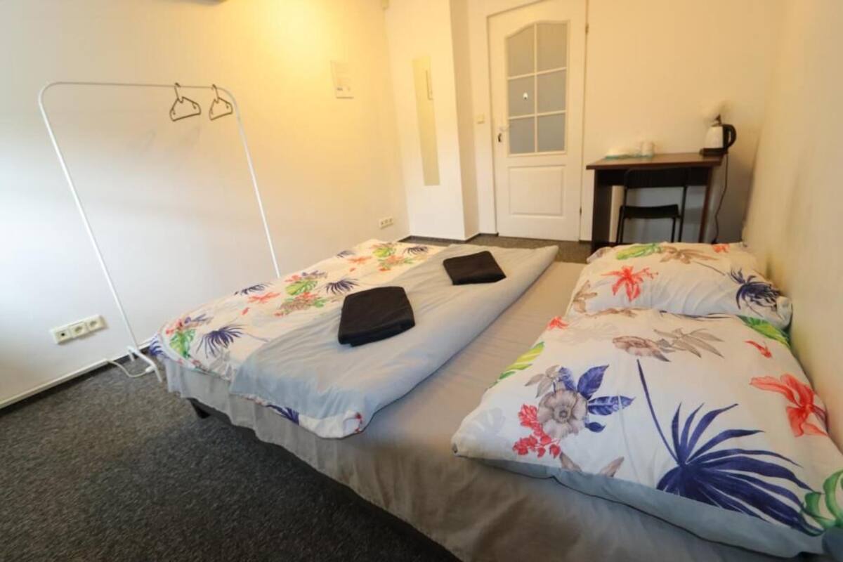 A small, simple room with two single beds, a desk, and a chair.