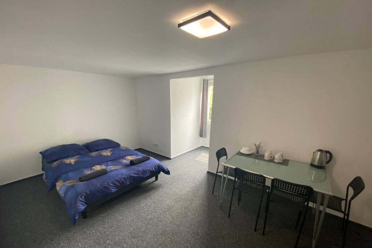 A room with a bed, a table, chairs, and a window.