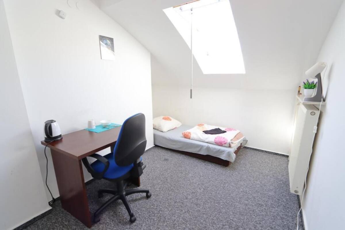 A small, compact room with a desk, chair, and a bed.