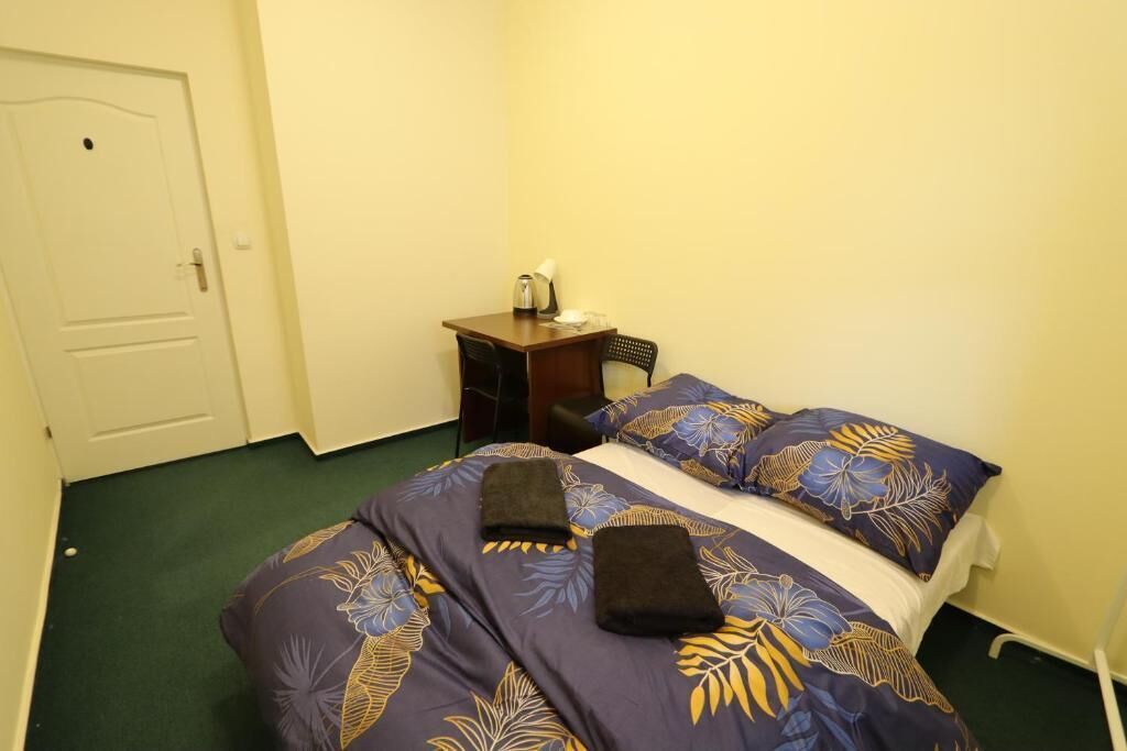 Une chambre d’hôtel avec un lit, une table de chevet, une chaise et une porte.