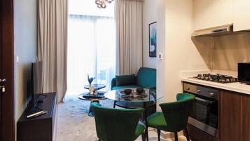 Una cucina moderna con fornello a gas, un'area pranzo con tavolo e sedie in vetro e un divano sullo sfondo.
