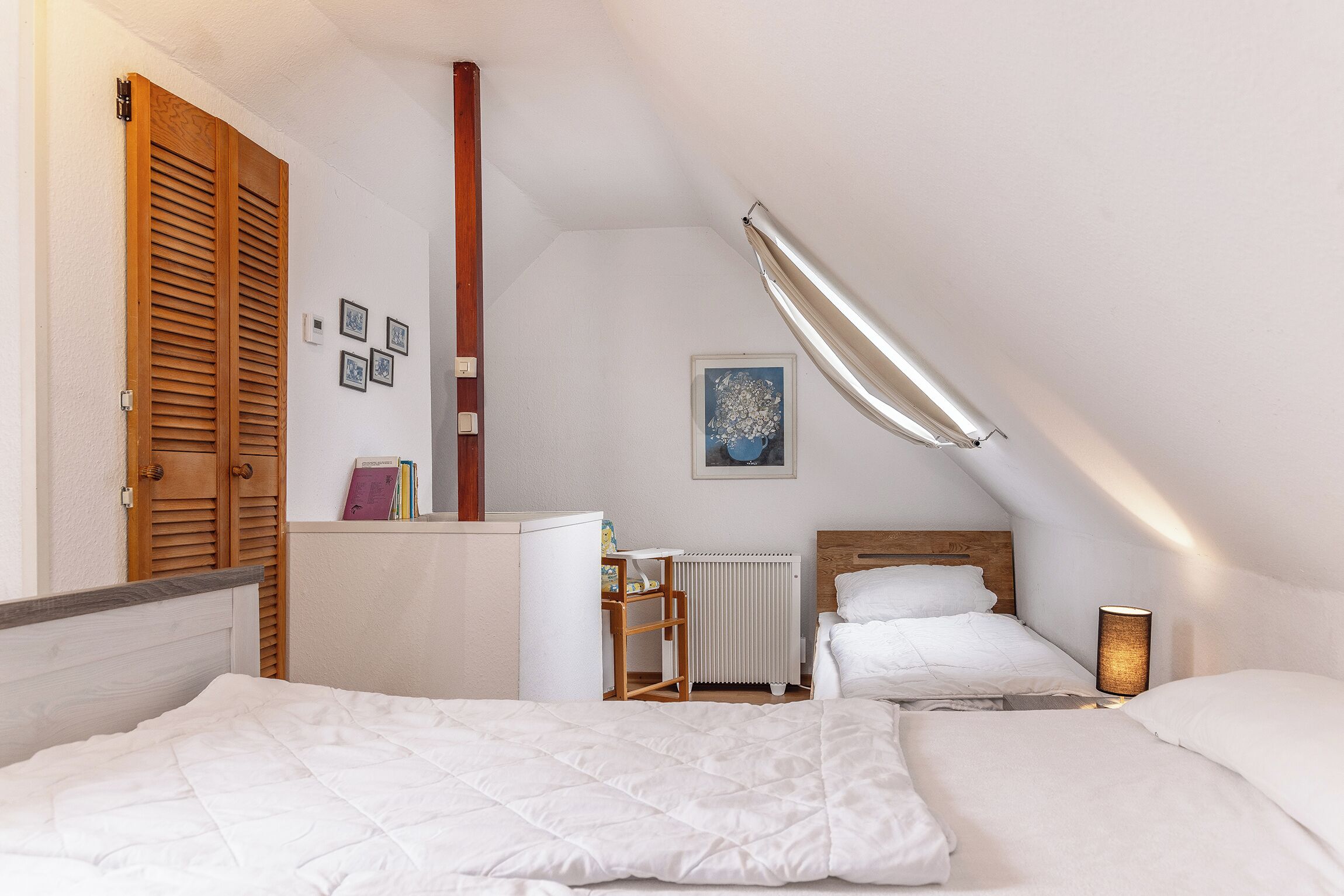 Ein Schlafzimmer mit zwei Betten, einem Heizkörper, einem Schreibtisch und einer Deckenleuchte.
