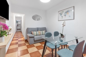 Ein modernes Wohnzimmer mit einem Glastisch, einem grauen Sofa und Sesseln.