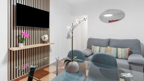 A modern living room with a flat-screen TV, a sofa, a glass coffee table, and a potted plant. - Holiday Home 'Casa Marbella' with Private Terrace, Wi-Fi and Air Conditioning (Fuengirola)