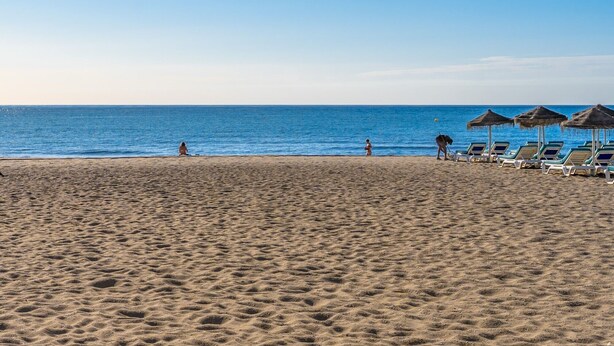 A beach with a clear sky, a sandy shore, and a row of beach chairs and umbrellas. - Holiday Home 'Casa Marbella' with Private Terrace, Wi-Fi and Air Conditioning (Fuengirola)