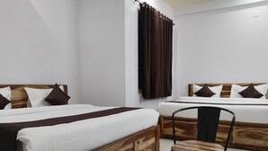 A hotel room with two wooden beds, a small wooden table, and a chair. - Hotel Yaduraj By Salasar Hospitality (Udaipur)
