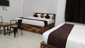 A hotel room with two beds, a wooden headboard, a desk, and a chair. - Hotel Yaduraj By Salasar Hospitality (Udaipur)