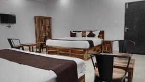 A bedroom with two wooden beds, a TV, a wardrobe, and a desk with chairs. - Hotel Yaduraj By Salasar Hospitality (Udaipur)