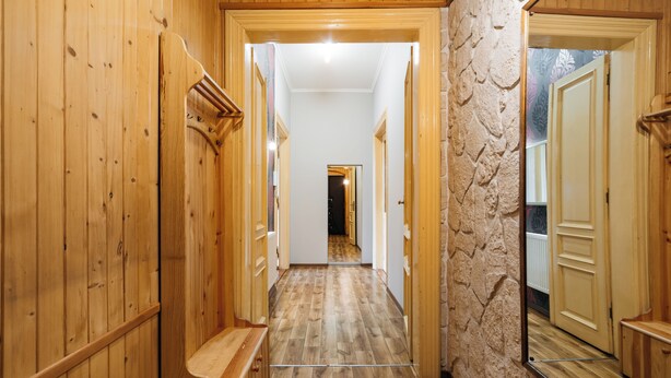 Un corridoio in legno con una parete in pietra e una porta in fondo.