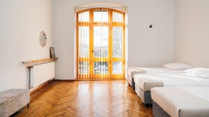 Camera da letto con pavimento in legno, due letti, un termosifone e una finestra con stipite in legno.