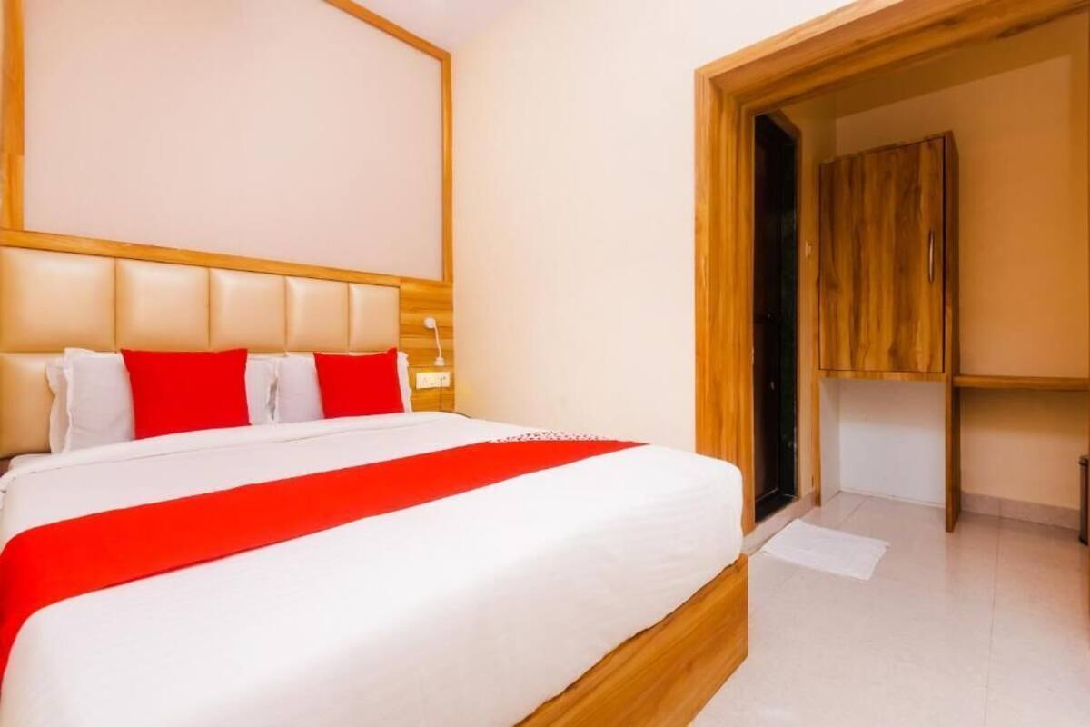 A hotel room with a large bed, a wooden headboard, and a wardrobe.