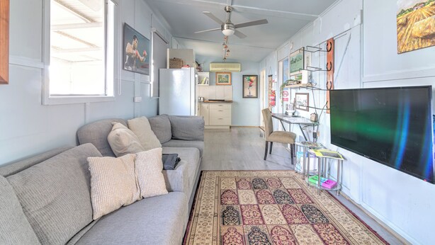 A living room with a sofa, a television, a ceiling fan, and a patterned rug.
