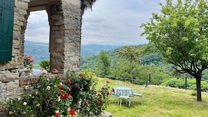 Un bâtiment en pierre offrant une vue sur une vallée verdoyante.