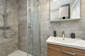 Apartamento Deluxe, balcón, vistas parciales al mar | Baño | Ducha, secador de pelo, toallas y papel higiénico