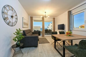 Apartamento Deluxe, balcón, vistas parciales al mar | Zona de estar | Una televisión