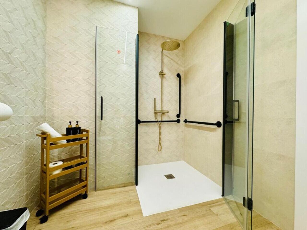 Une salle de bain moderne avec une douche à parois de verre, un porte-serviettes en bois et un lavabo blanc.
