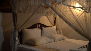 Un lit à baldaquin, avec une literie blanche et une tête de lit en bois.