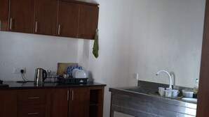 Een keuken met houten kastjes, een RVS spoelbak en een aanrecht met een waterkoker en servies.