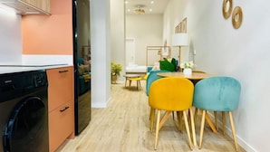 Una cuina compacta amb electrodomèstics moderns, una zona de dinar amb caires colorides i un interior net i lluminós.