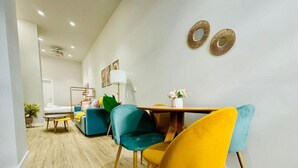 Una zona de menjador moderna amb una taula de fusta i cadires de colors, un sofà i una làmpada.