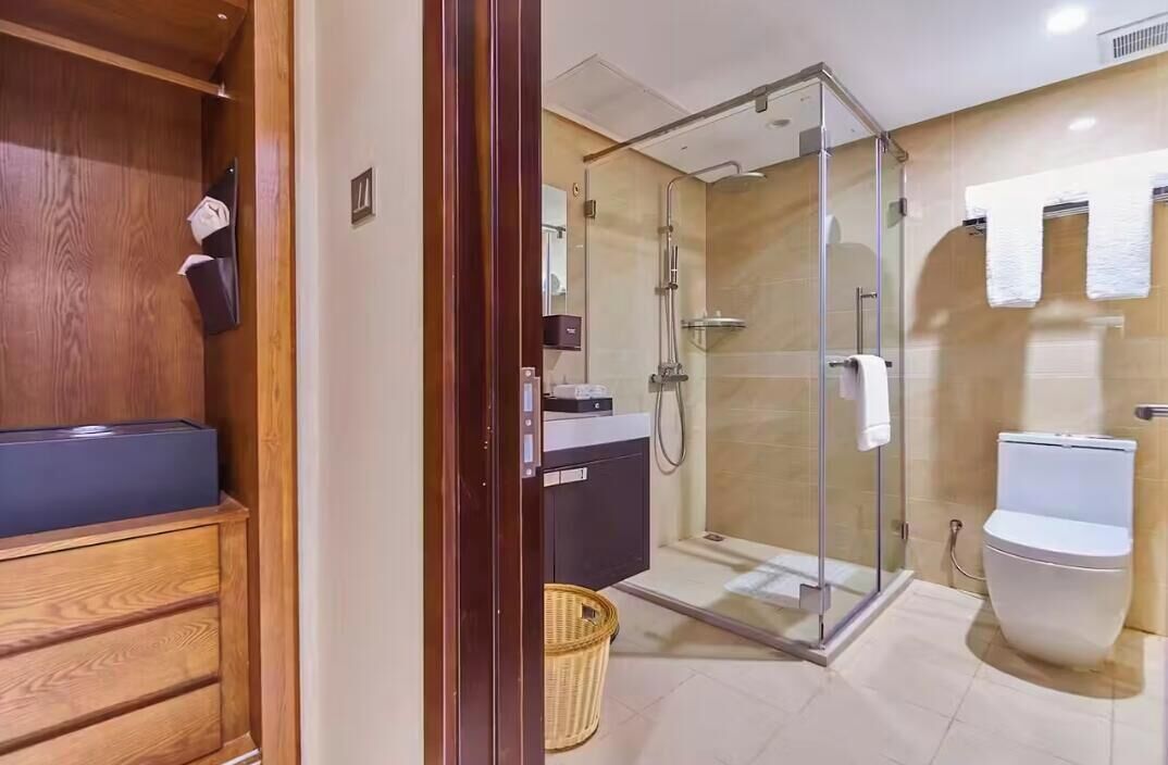 A modern bathroom with a glass-enclosed shower, a wooden vanity, and a white toilet.