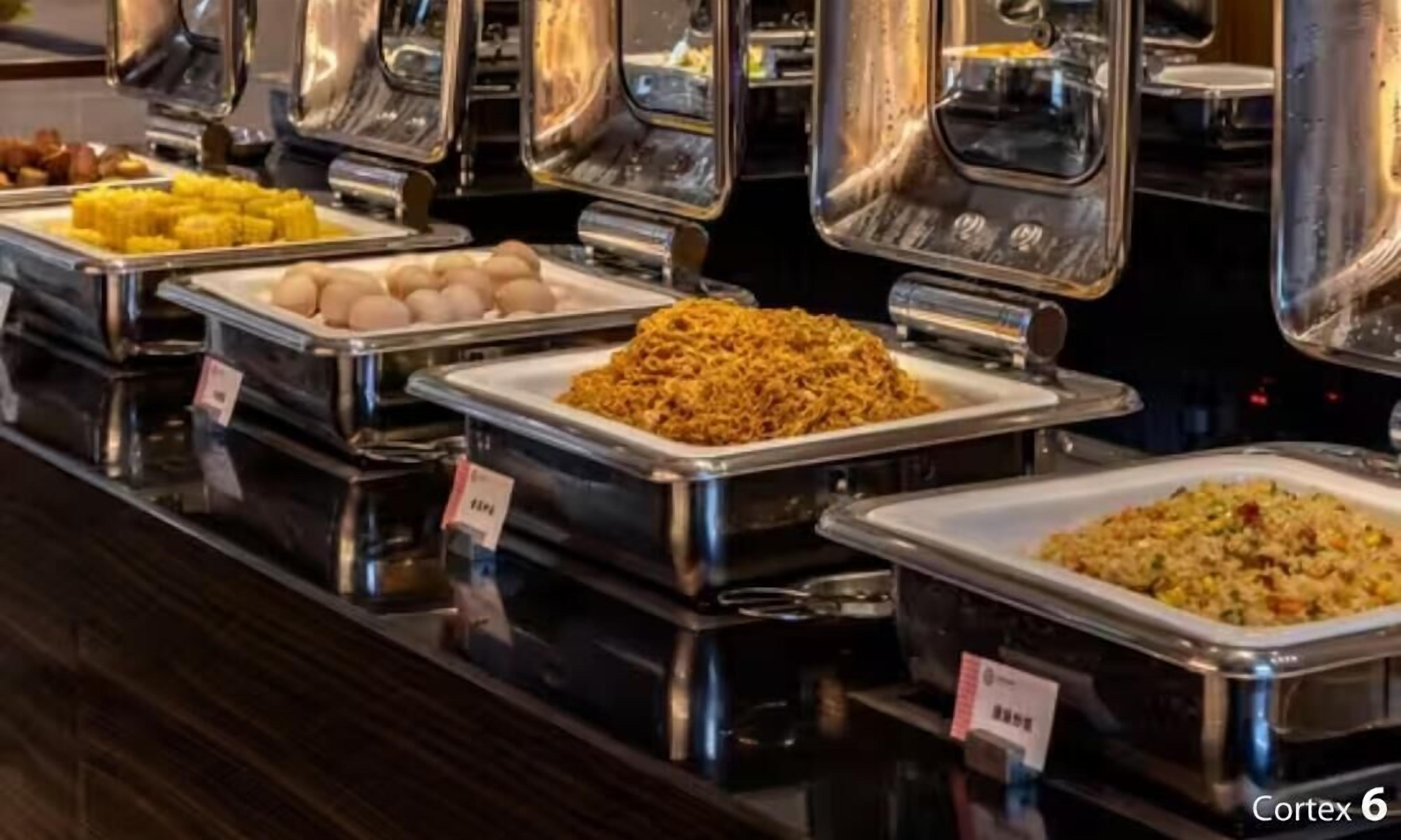 A buffet with various food items in metal containers, arranged on a polished black countertop.
