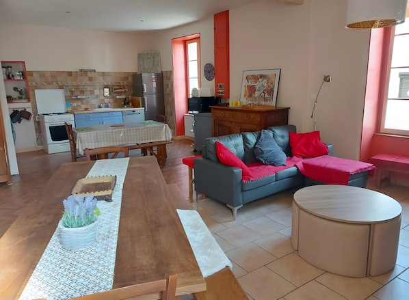 A modern kitchen with a dining table, a sofa, and a round table in a living area.