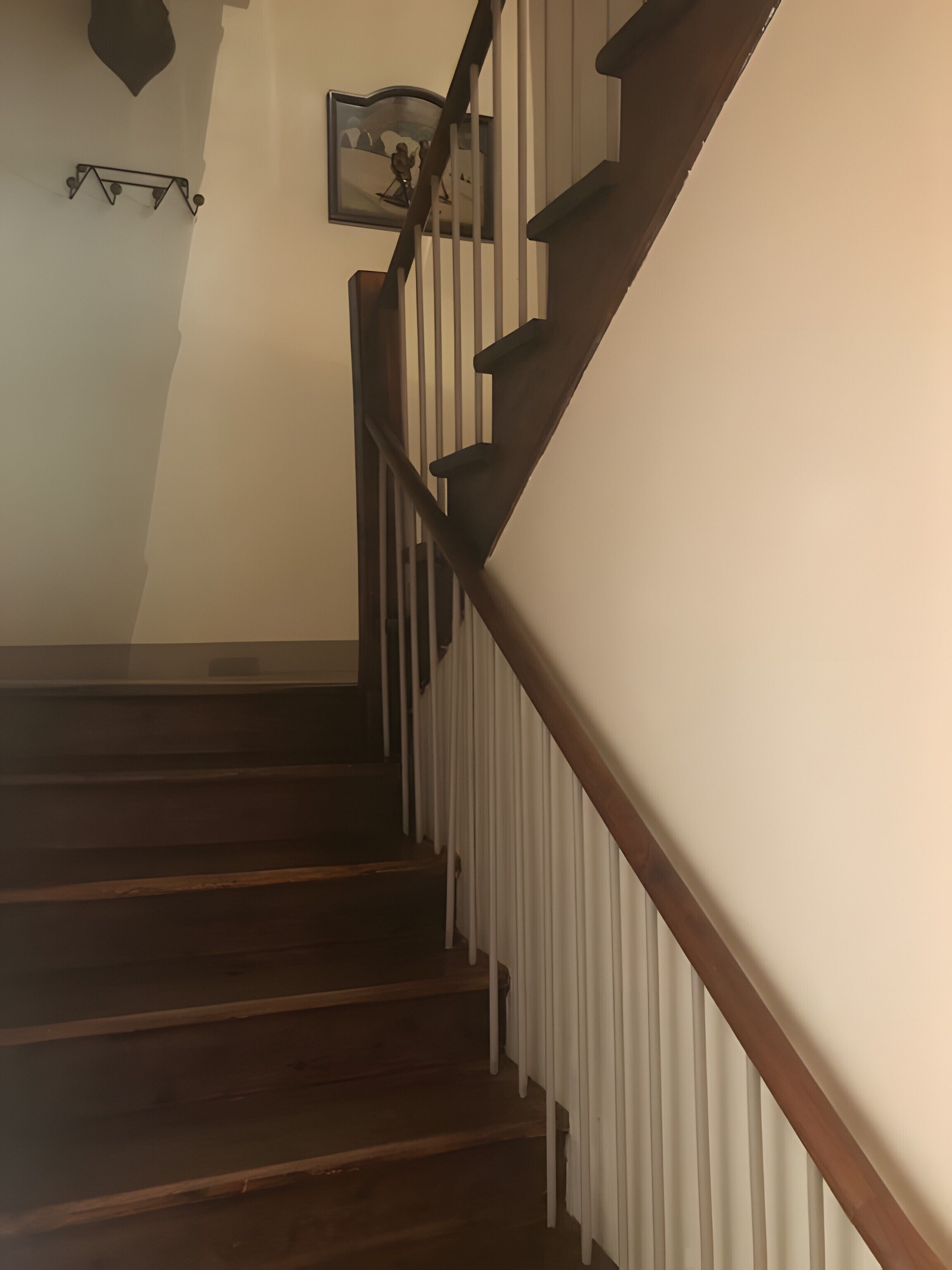 A wooden staircase with white balusters and a dark handrail.