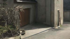 Un bâtiment à deux étages, doté d’un toit en pente, d’une porte de garage et d’un petit espace porche.
