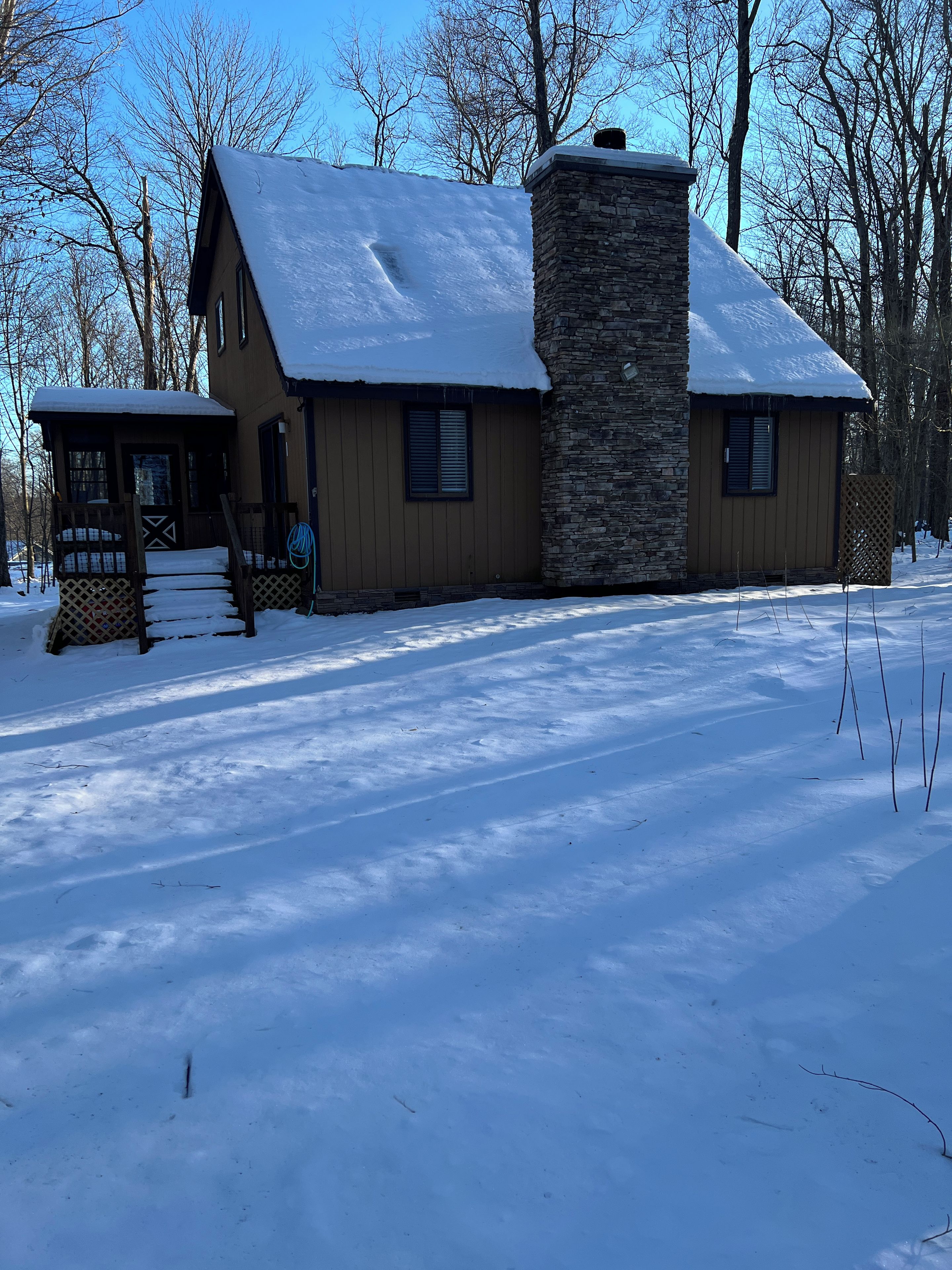 Ein zweistöckiges Haus mit einem Steinsschornstein, Holzverkleidung und einem mit Schnee bedeckten Dach.