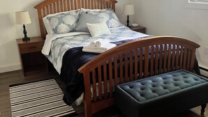 A bedroom with a wooden bed, a bench, a nightstand, a lamp, and a painting on the wall. - 3-bedroom house in superb Big Bass Lake with AC (Big Bass Lake)