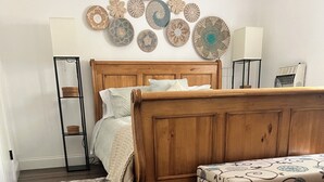 A bedroom with a wooden bed, a bench, a fur rug, a wall-mounted lamp, and decorative plates. - 3-bedroom house in superb Big Bass Lake with AC (Big Bass Lake)