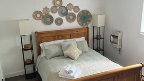 A bedroom with a wooden bed, a bedside lamp, a wall-mounted heater, and decorative plates. - 3-bedroom house in superb Big Bass Lake with AC (Big Bass Lake)