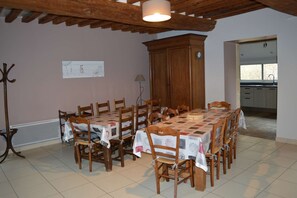 A dining area with a long wooden table, chairs, a wooden cabinet, and a clock on the wall. - My family home, 18th century barn, garden (Colombiers-sur-Seulles)