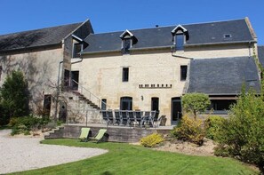 A two-story stone building with a balcony and outdoor seating area. - My family home, 18th century barn, garden (Colombiers-sur-Seulles)