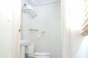 Une salle de bain équipée de toilettes, d’une douche et d’un porte-serviettes.